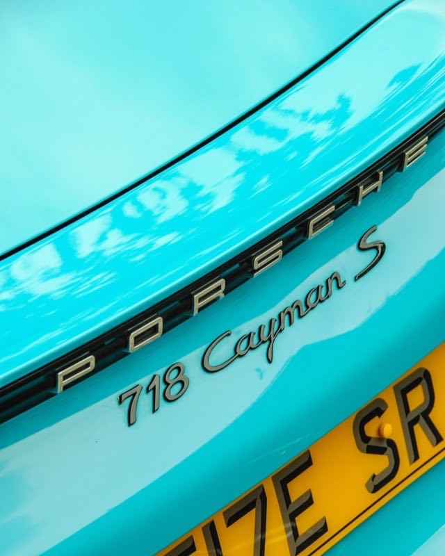 Close-up of the 718 Cayman S badge on the turquoise tail of a Porsche