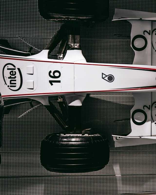 The white nose and front wing of a BMW Sauber Formula One car mounted on a dark perforated wall, carrying the number 16