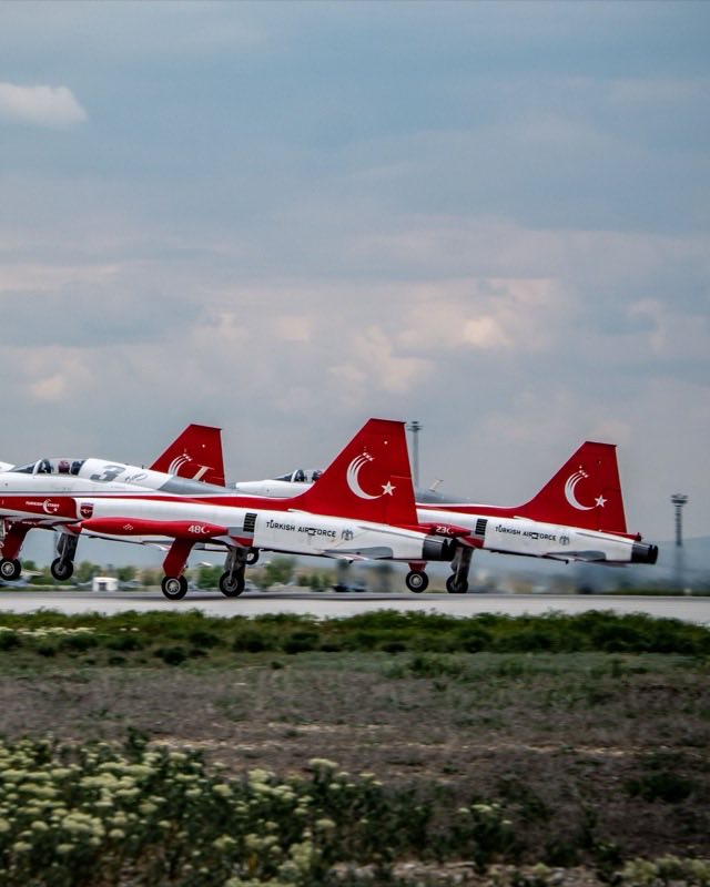 Three red and white Turkish Air Force NF-5 jets on a runway, tails marked with the Turkish crescent and star