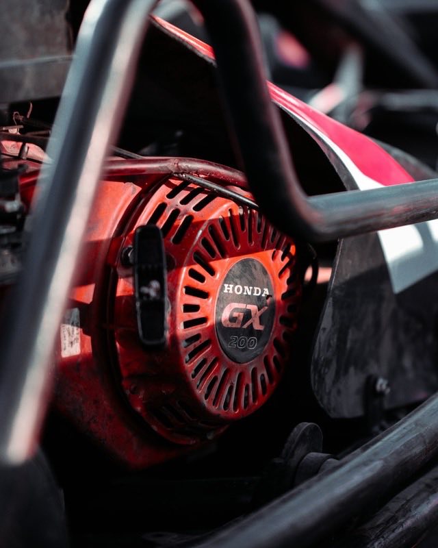 A red Honda GX pull-start engine bolted inside a tubular steel frame