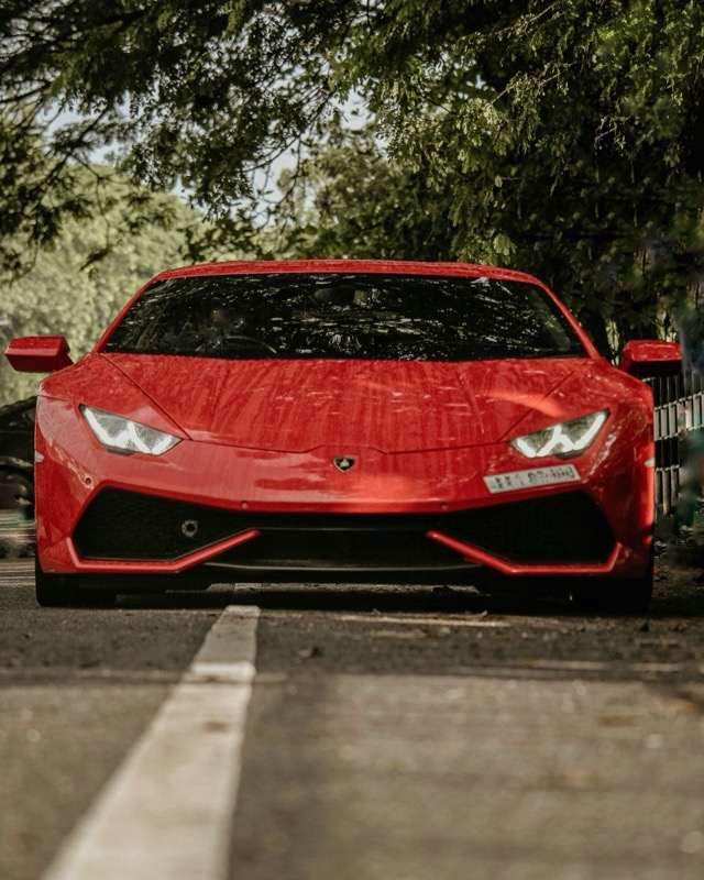 A red Lamborghini Huracán seen head-on on a road under overhanging trees