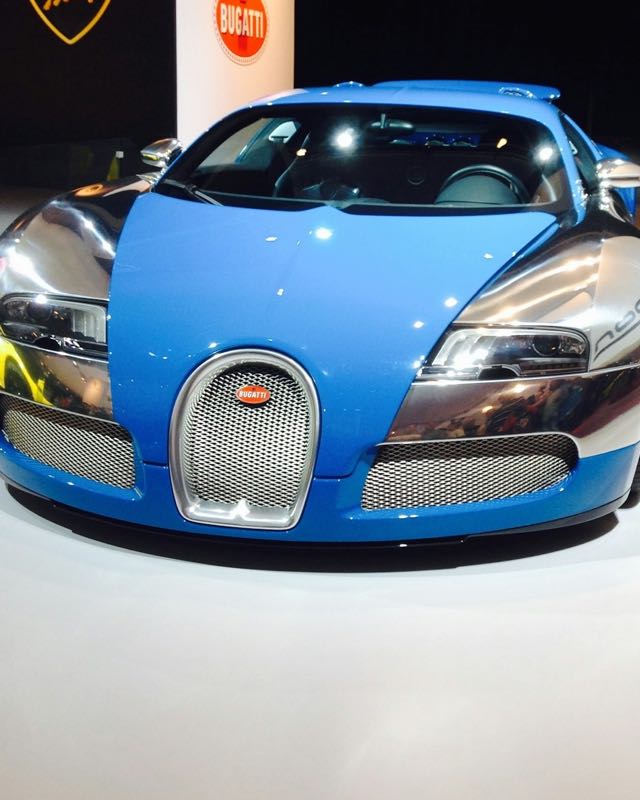 A blue and polished-aluminium Bugatti Veyron 16.4 seen head-on at a motor show